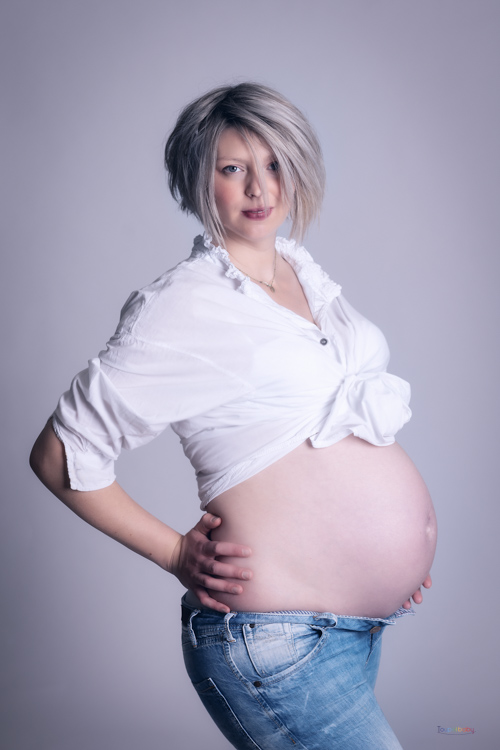 jeune femme enceinte pose en jean avec un top blanc